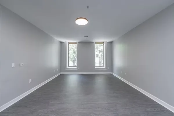 a view of an empty room with a window and wooden floor