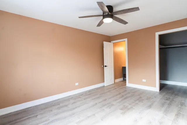 an empty room with wooden floor and a ceiling fan