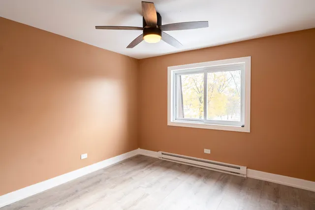 an empty room with a window and a fan
