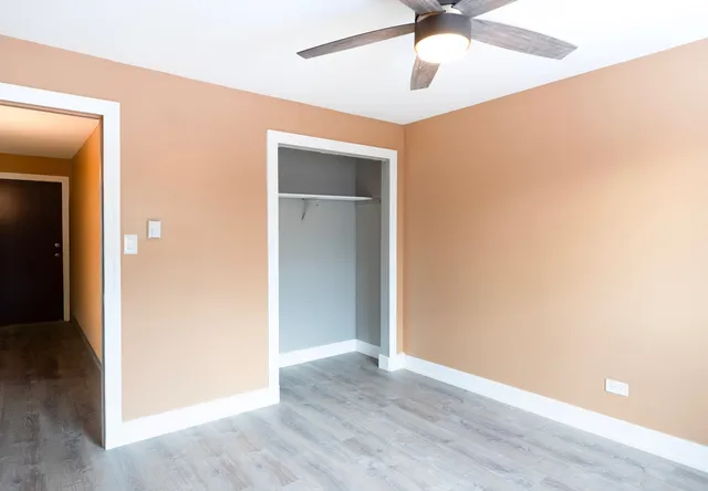 a view of an empty room with a ceiling fan and wooden floor