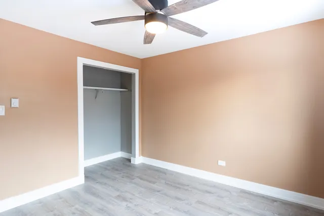 an empty room with a ceiling fan and wooden floor