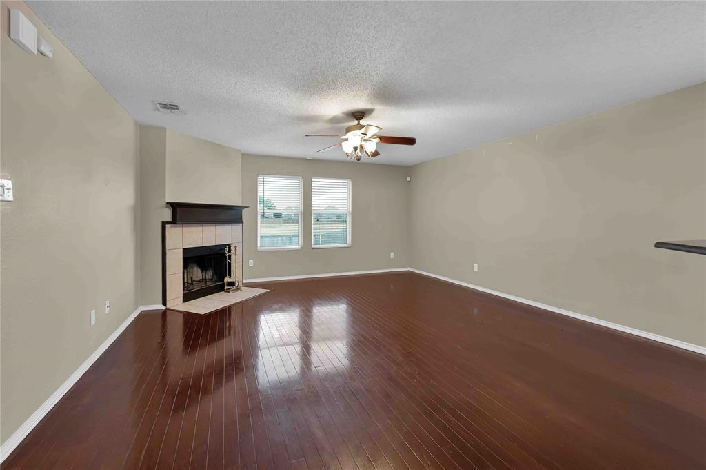 9517 George Washington Drive McKinney, TX 75072 - Photo 6 of 31 an empty room with wooden floor fireplace and windows