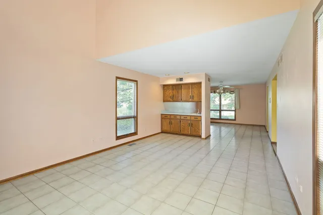 a view of an empty room with kitchen and a window