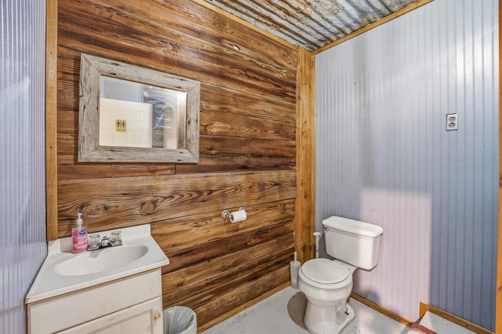1262 Rosser Ranch Road Graham, TX 76450 - Photo 27 of 39 a bathroom with a toilet sink vanity and mirror