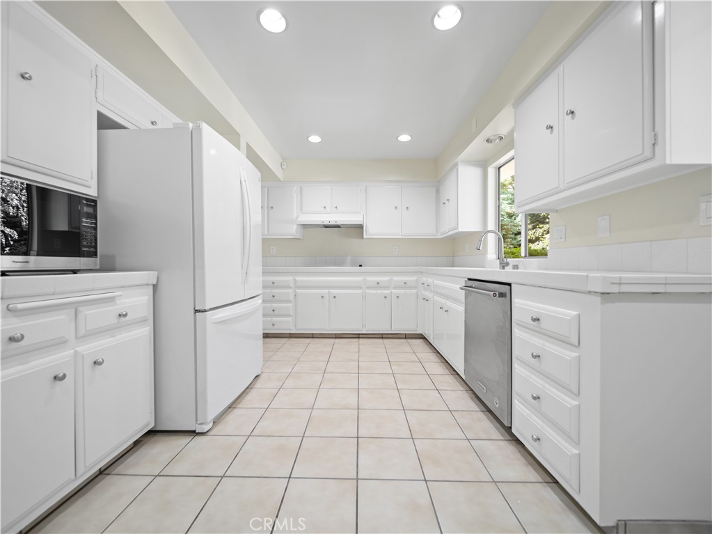 a kitchen with white cabinets a sink appliances and a window