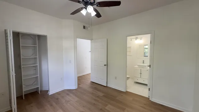 an empty room with wooden floor closet and windows