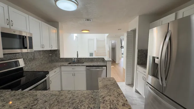 a kitchen with stainless steel appliances granite countertop a refrigerator stove and sink