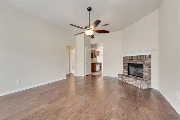 a view of an empty room with a fireplace and a fan