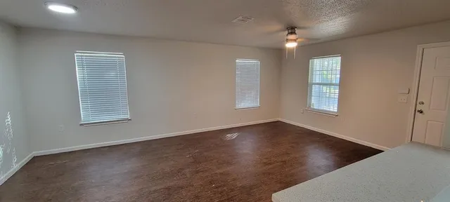an empty room with wooden floor and windows