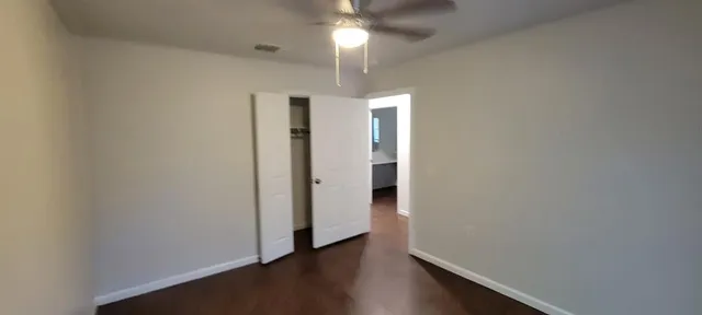 an empty room with wooden floor chandelier fan and closet