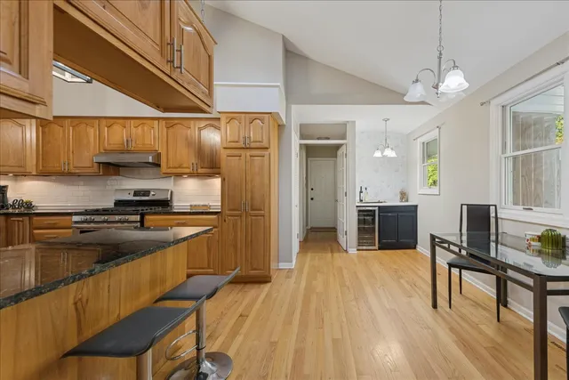 a kitchen with stainless steel appliances granite countertop a refrigerator a sink dishwasher a stove and white cabinets with wooden floor