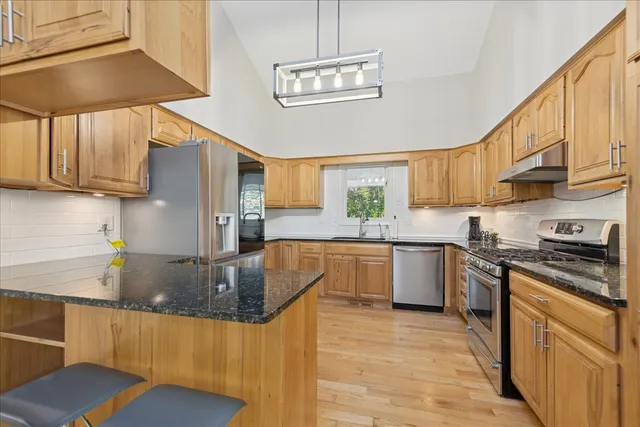 a kitchen with stainless steel appliances granite countertop a stove a sink dishwasher and a refrigerator