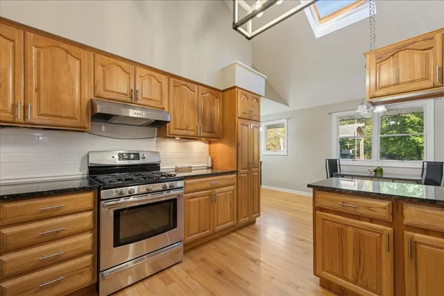a kitchen with stainless steel appliances granite countertop a sink a stove a refrigerator cabinets and a window