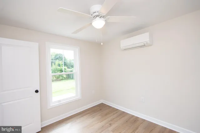 an empty room with a window and a fan