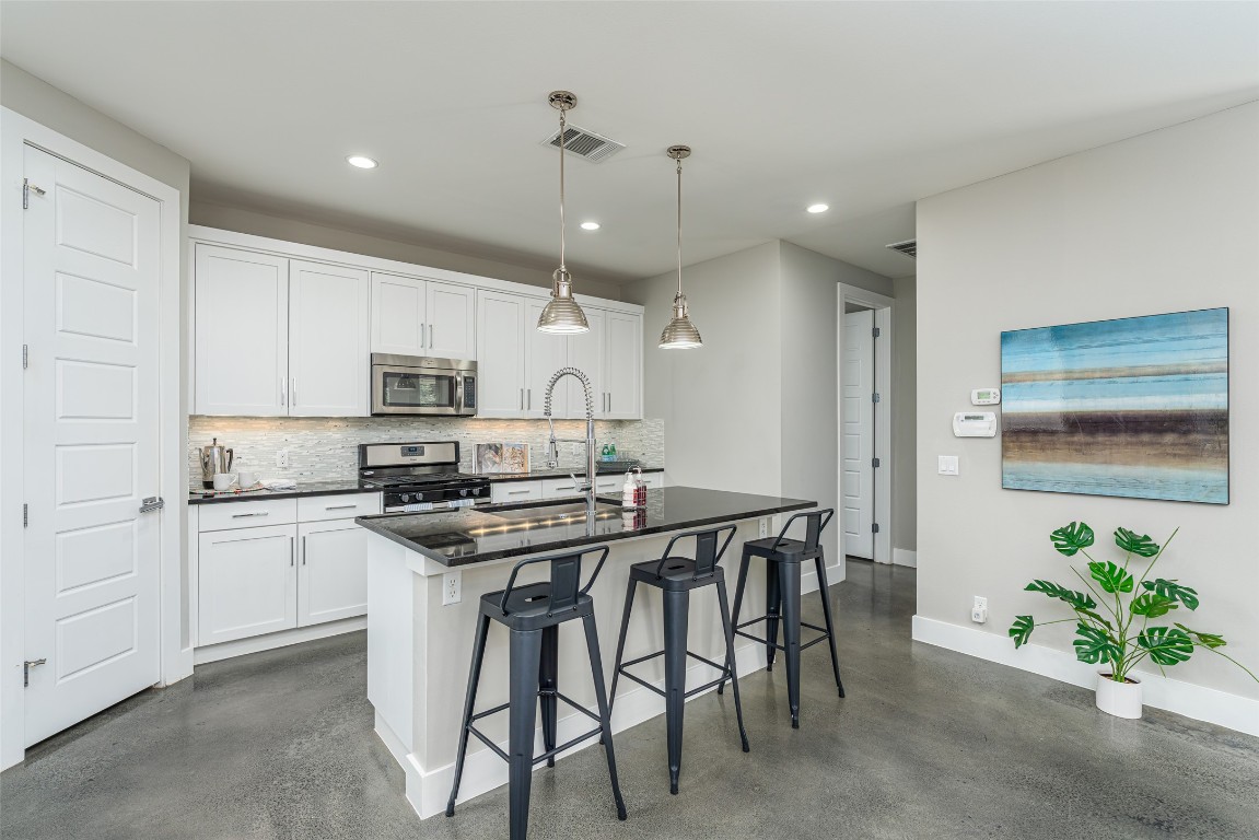 705 East 49th Street, Unit A Austin, TX 78751 - Photo 11 of 39 a kitchen with stainless steel appliances a white table chairs refrigerator and sink