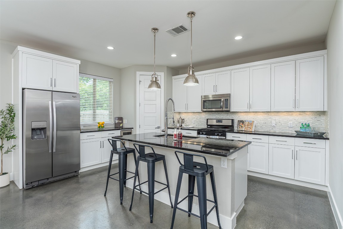 705 East 49th Street, Unit A Austin, TX 78751 - Photo 10 of 39 a kitchen with stainless steel appliances granite countertop a stove a refrigerator a sink a dining table and chairs