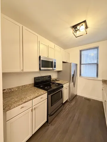 a kitchen with granite countertop a stove a sink and a refrigerator