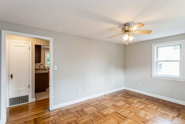 a view of a big room with wooden floor and a chandelier fan