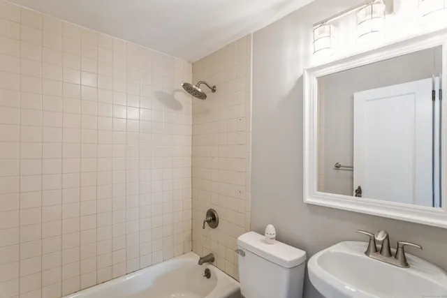 a bathroom with a toilet a sink a mirror and shower