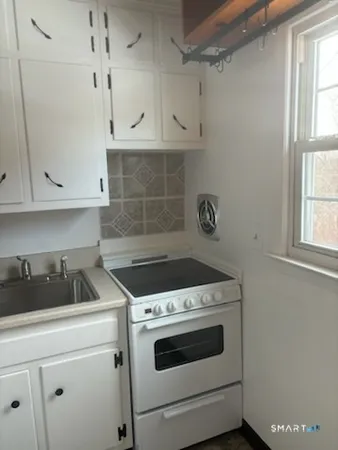 a kitchen with white cabinets and white stove