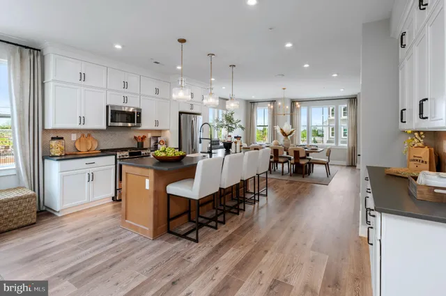 a living room with stainless steel appliances furniture a dining table and kitchen view