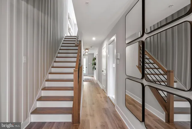 a view of staircase with lots of frames on wall and wooden floor