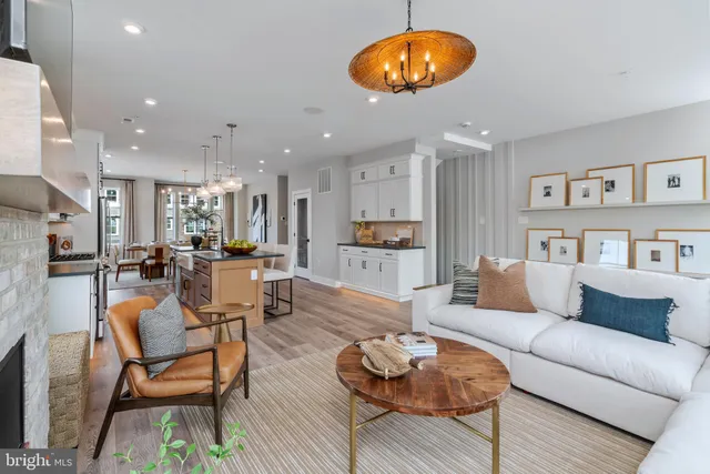 a living room with furniture kitchen view and a wooden floor