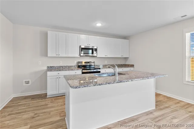 a kitchen with stainless steel appliances granite countertop a sink a stove and a refrigerator