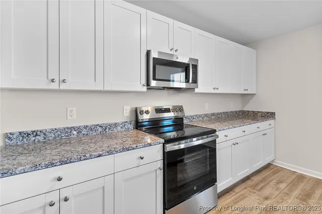a kitchen with granite countertop white cabinets and stainless steel appliances