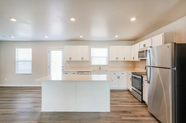 a kitchen with a refrigerator a sink and dishwasher with wooden floor