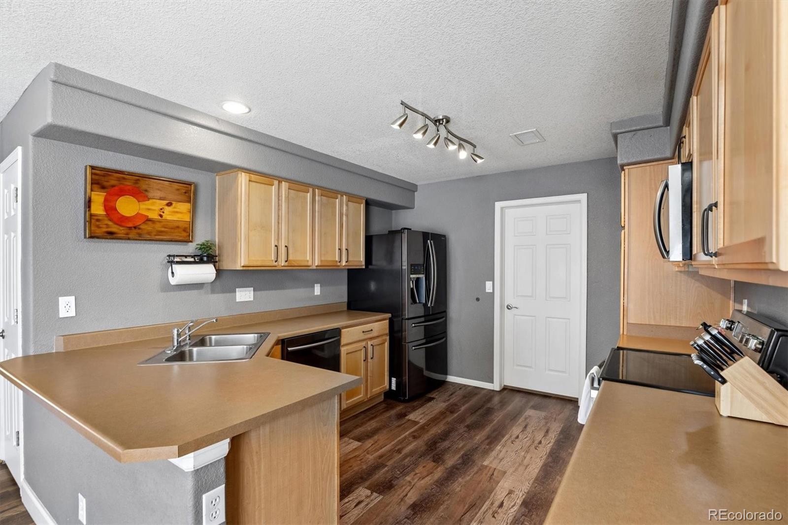 4983 Halifax Court Denver, CO 80249 - Photo 6 of 17 a kitchen with stainless steel appliances granite countertop a sink a stove and a refrigerator