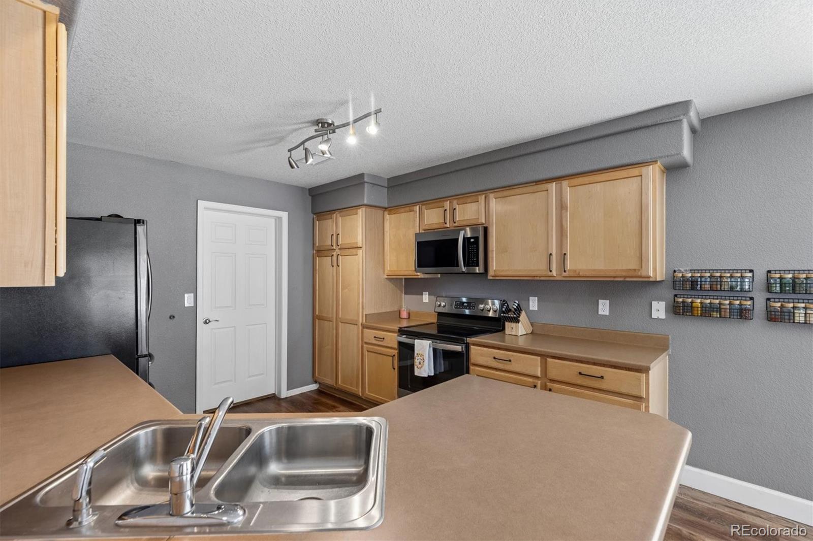 4983 Halifax Court Denver, CO 80249 - Photo 7 of 17 a kitchen with stainless steel appliances a sink a stove a microwave and cabinets