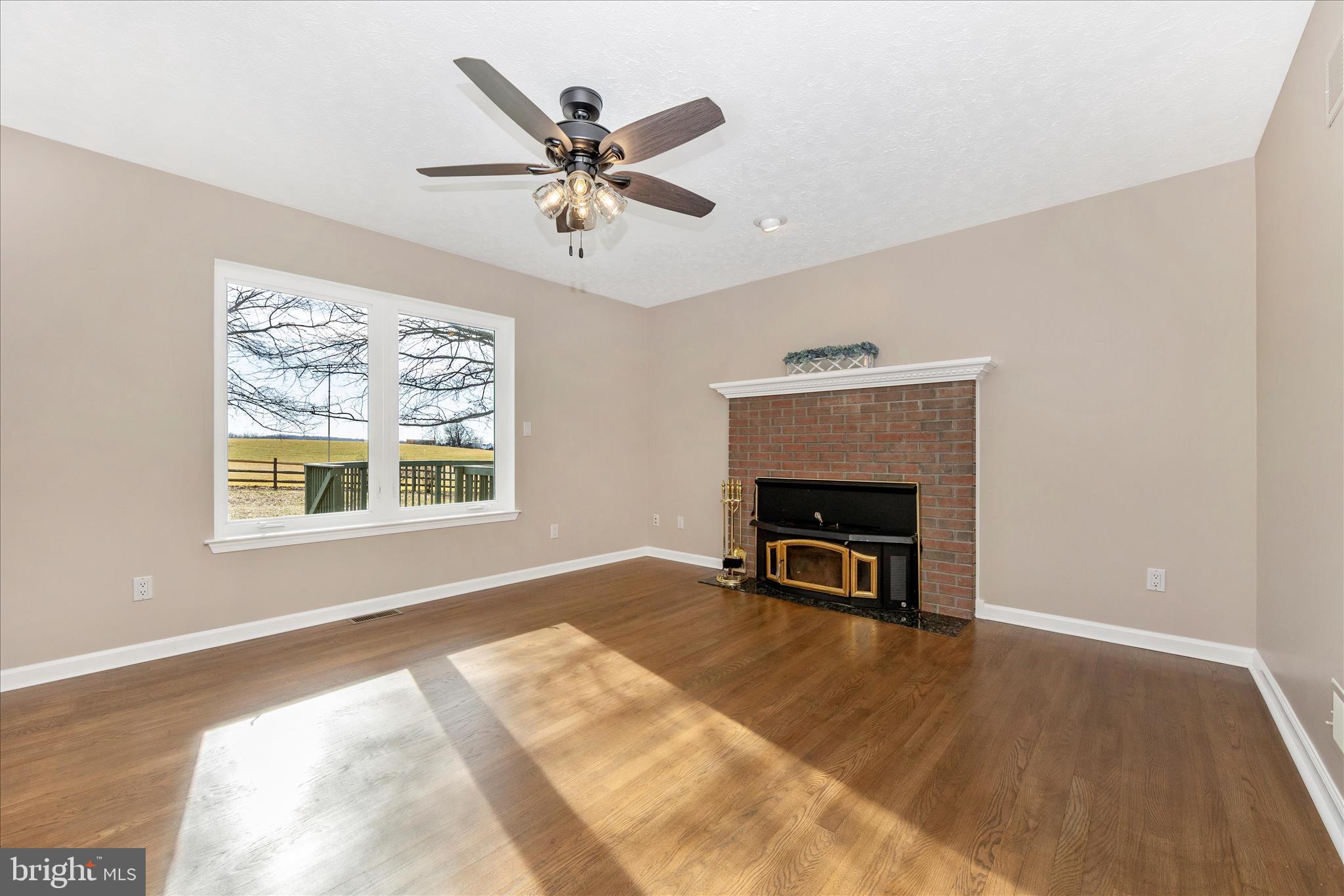 14695 Oak Orchard Road New Windsor, MD 21776 - Photo 23 of 57 a view of a livingroom with a fireplace a ceiling fan and wooden floor