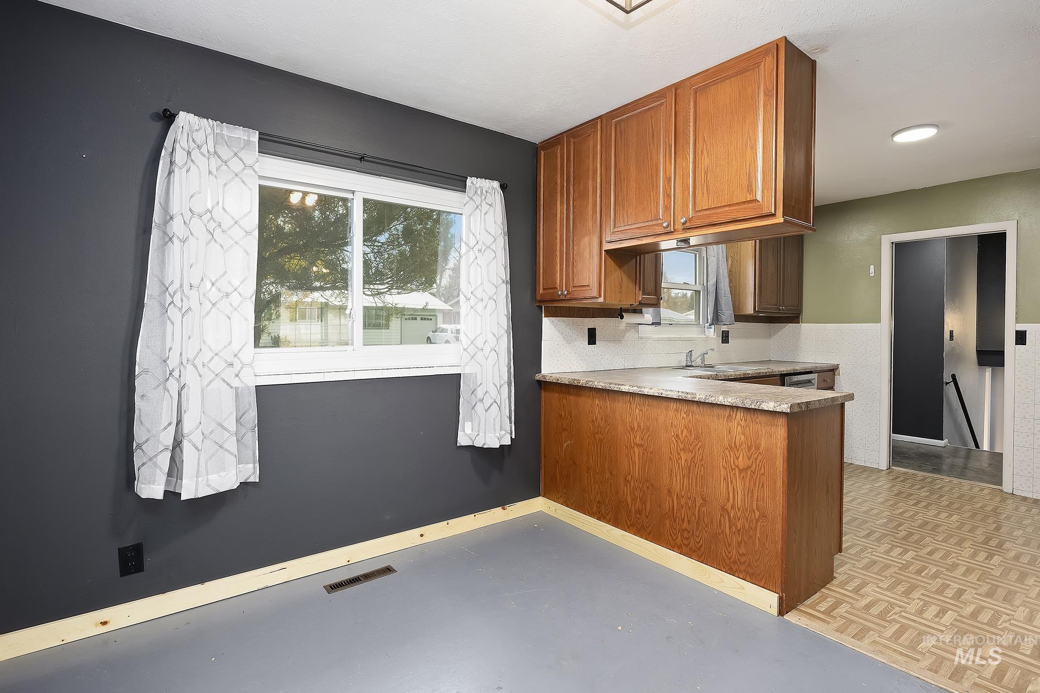320 East 23rd Drive Burley, ID 83318 - Photo 11 of 34 Kitchen with brown cabinets, light countertops, a peninsula, and tasteful backsplash