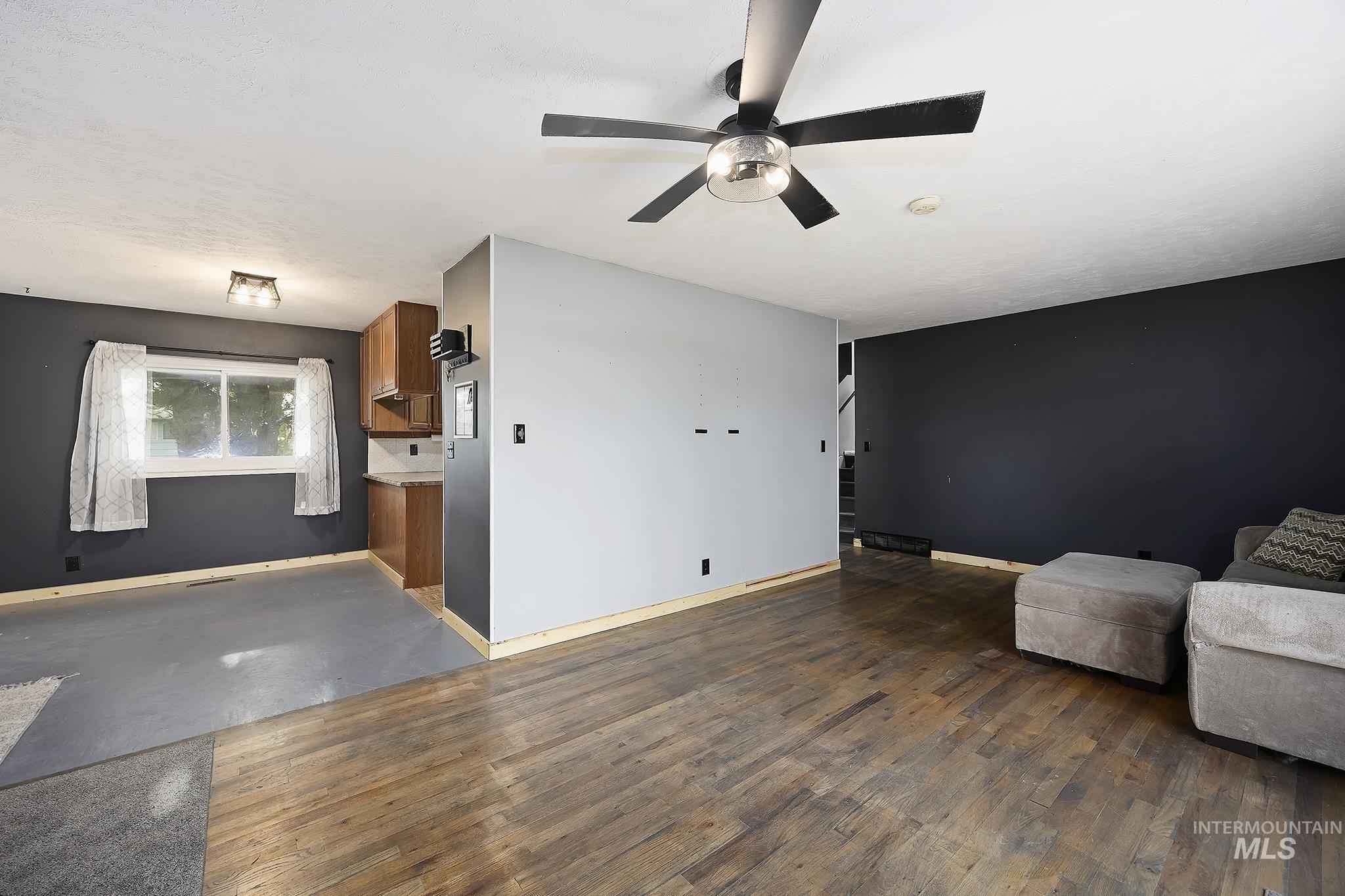 320 East 23rd Drive Burley, ID 83318 - Photo 9 of 34 Unfurnished room featuring ceiling fan, dark wood-style flooring, and stairway