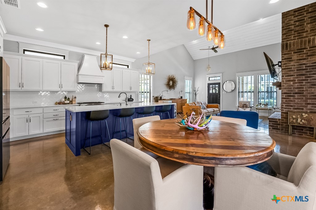 659 Prospect Way New Braunfels, TX 78130 - Photo 16 of 32 a dining room with stainless steel appliances kitchen island granite countertop a table chairs and a refrigerator