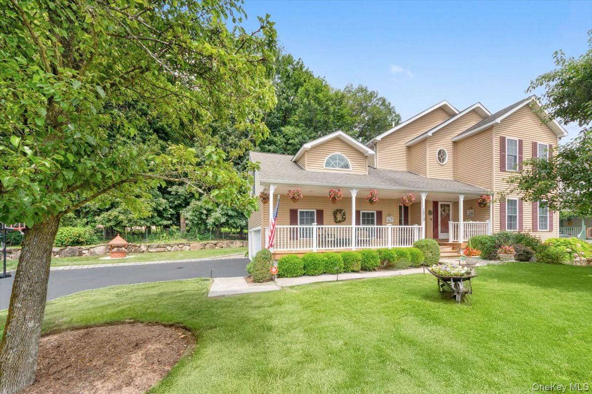 View of front of home with a porch, a front yard, a shingled roof, and a garage