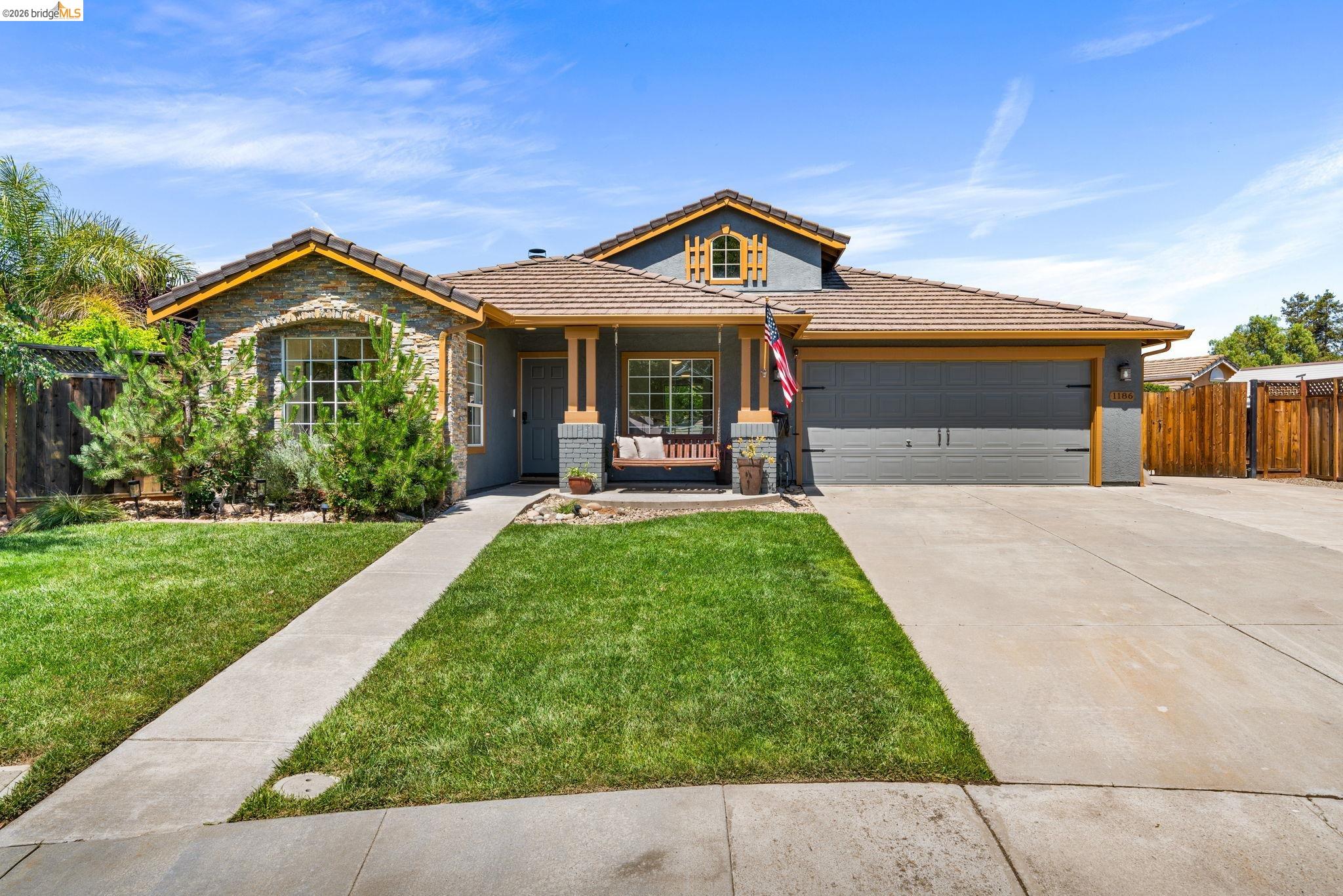1186 El Rio Court Livermore, CA 94551 - Photo 60 of 60 Contemporary exterior featuring stone facade accents, a concrete driveway, an attached two-car garage, and a covered front porch with pillar supports