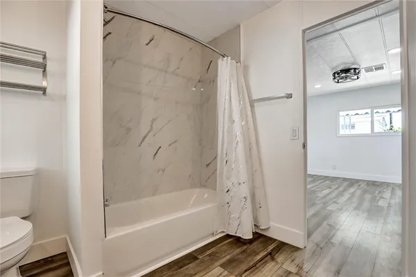 an empty room with wooden floor and a kitchen
