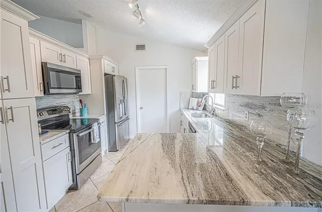 a kitchen with stainless steel appliances granite countertop a refrigerator stove microwave and sink