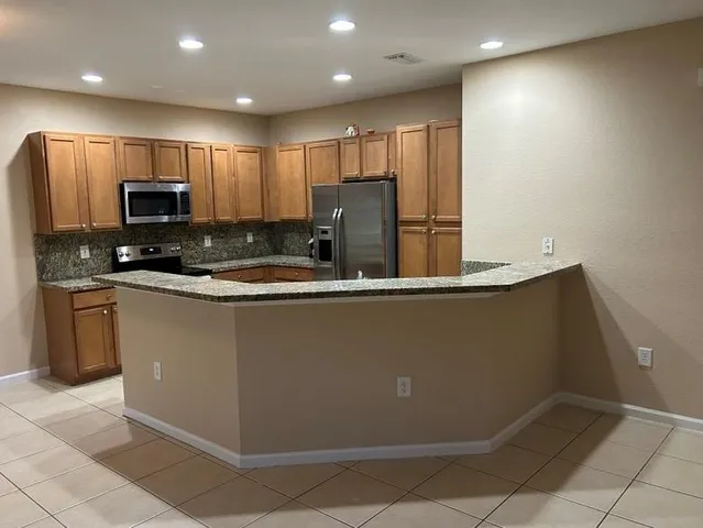 a kitchen with stainless steel appliances granite countertop a refrigerator a stove a sink and a microwave