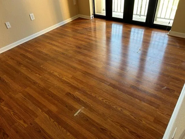 a view of an empty room with wooden floor and a window