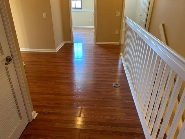 a view of a hallway with wooden floor and staircase