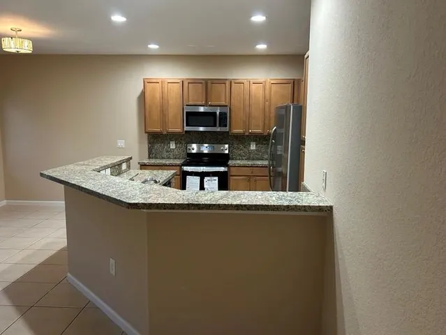 a view of a kitchen with stainless steel appliances granite countertop a sink and a refrigerator