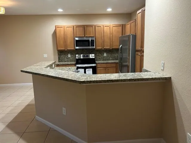 a kitchen with kitchen island granite countertop a sink a stove and refrigerator