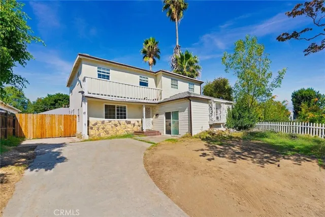 a front view of a house with a yard and potted plants