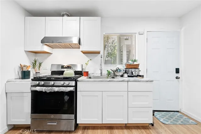 a kitchen with stainless steel appliances a stove and white cabinets