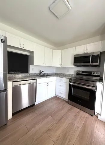 a kitchen with granite countertop a stove top oven and cabinets