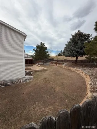 a view of a dry yard with wooden fence