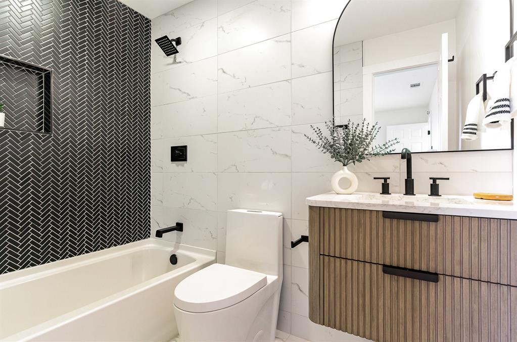 7524 Aberdon Road Dallas, TX 75252 - Photo 23 of 39 Bathroom featuring toilet, shower combination, tile walls, and vanity